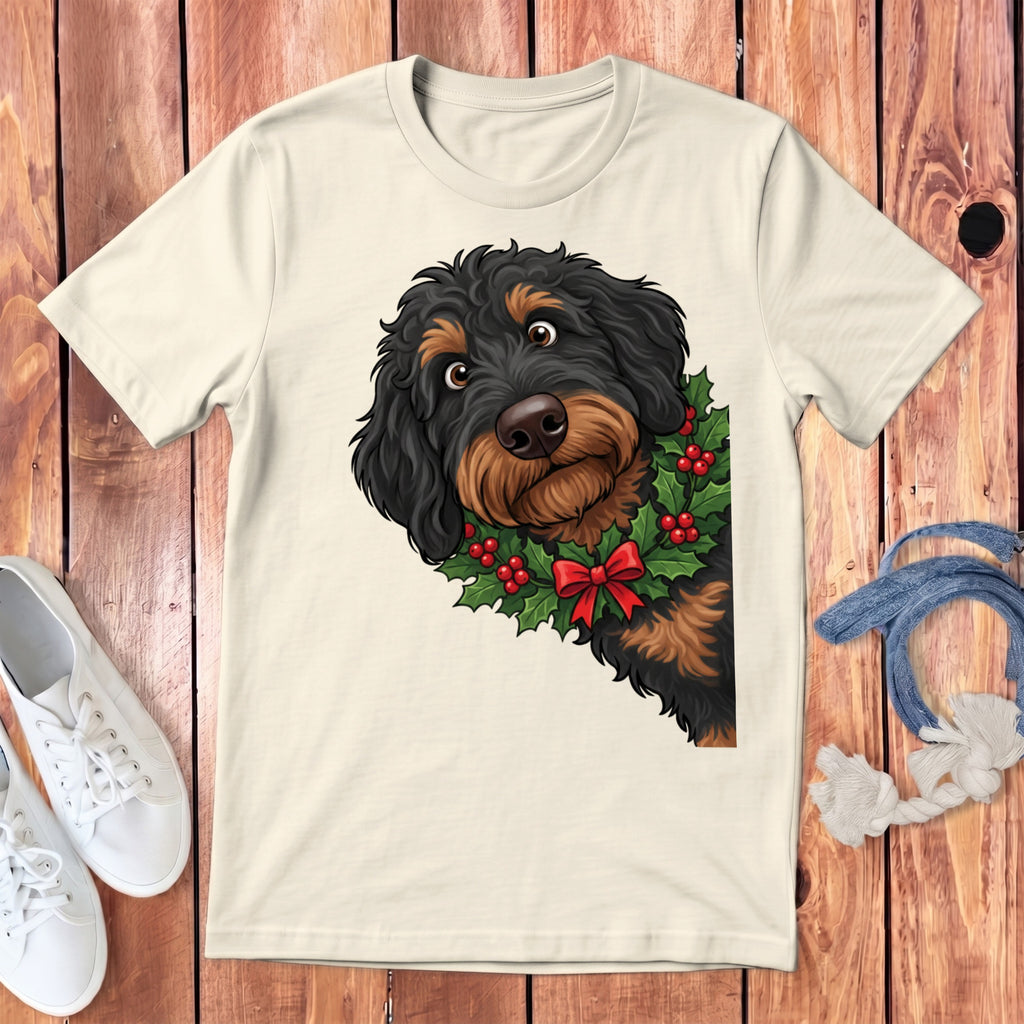 Cream t-shirt with black and brown dog wearing a holly wreath and red bow.