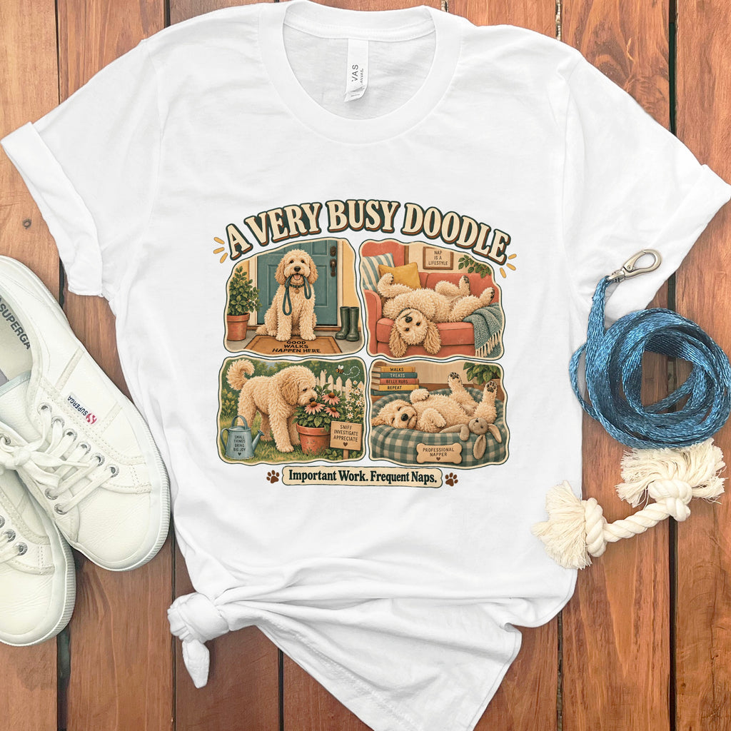 White t-shirt with "A Very Busy Doodle" graphic showing four scenes of a dog's life.