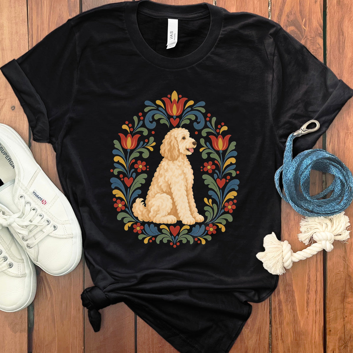 Black t-shirt with a cream-colored doodle dog inside a folk art floral wreath.