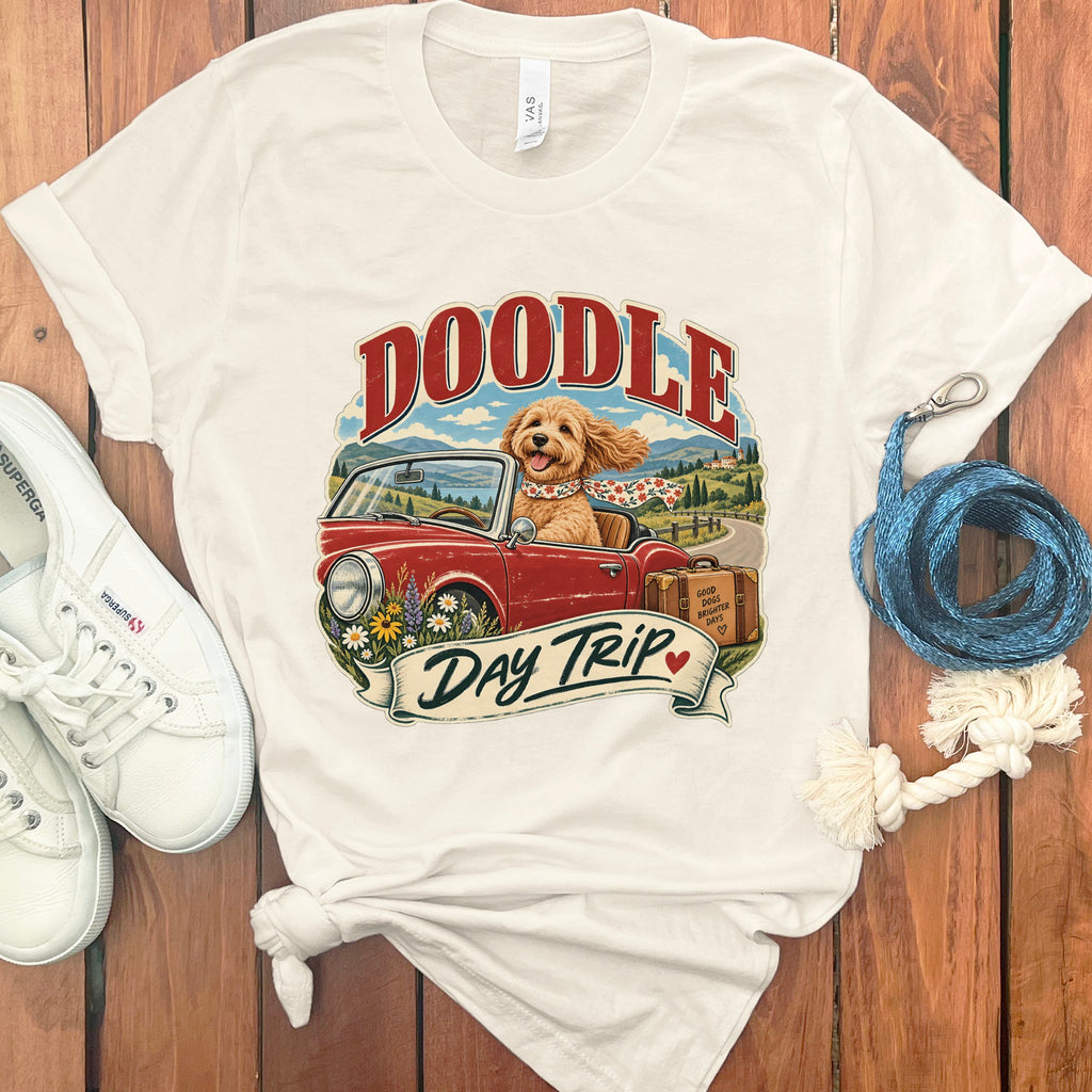 Cream t-shirt with "Doodle Day Trip" graphic of a dog in a convertible.