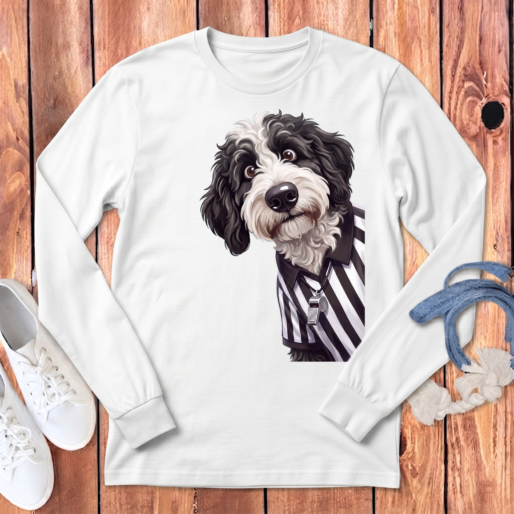 Black and white dog wearing a referee shirt with a whistle on a white long-sleeve shirt.