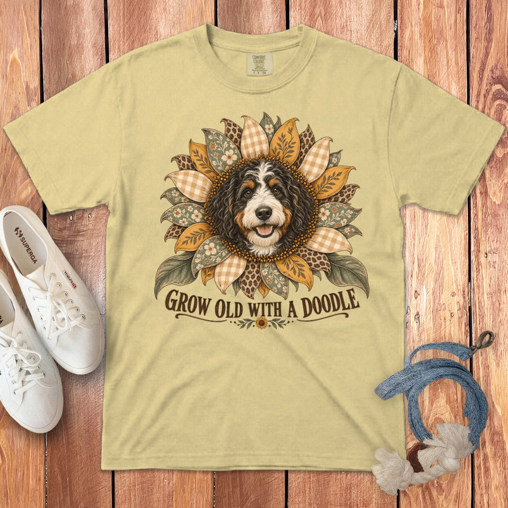 A light yellow t-shirt with a Bernedoodle surrounded by patterned petals and the text GROW OLD WITH A DOODLE.
