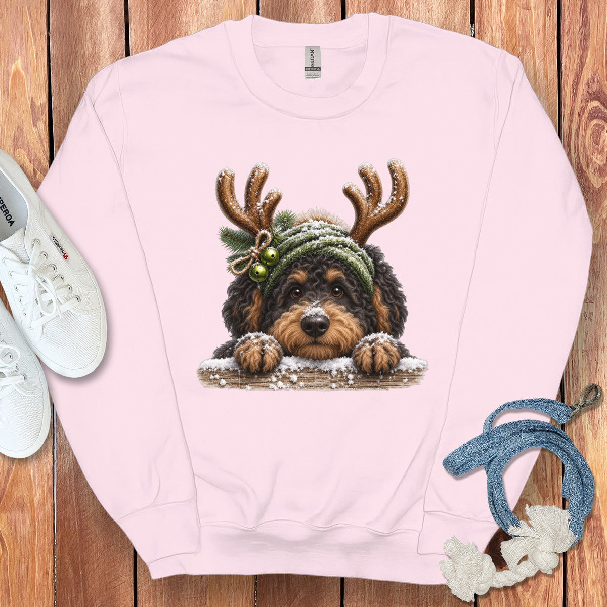 Pink crewneck sweatshirt with a doodle dog wearing reindeer antlers and a green beanie.