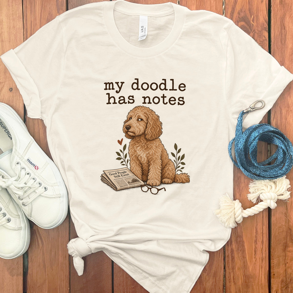 Cream t-shirt with doodle dog, newspaper, and glasses graphic and "my doodle has notes" text.