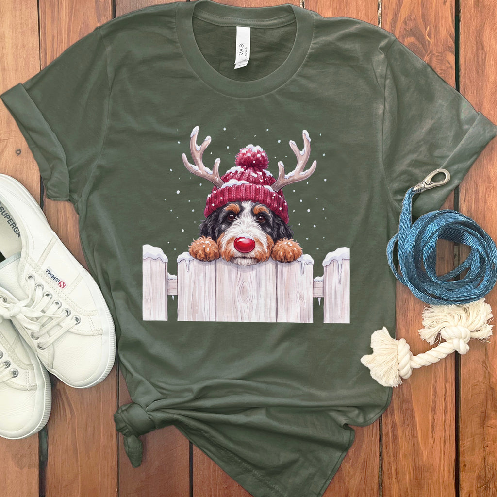 Bernese Mountain Dog in a Santa hat and reindeer antlers peeking over a fence.