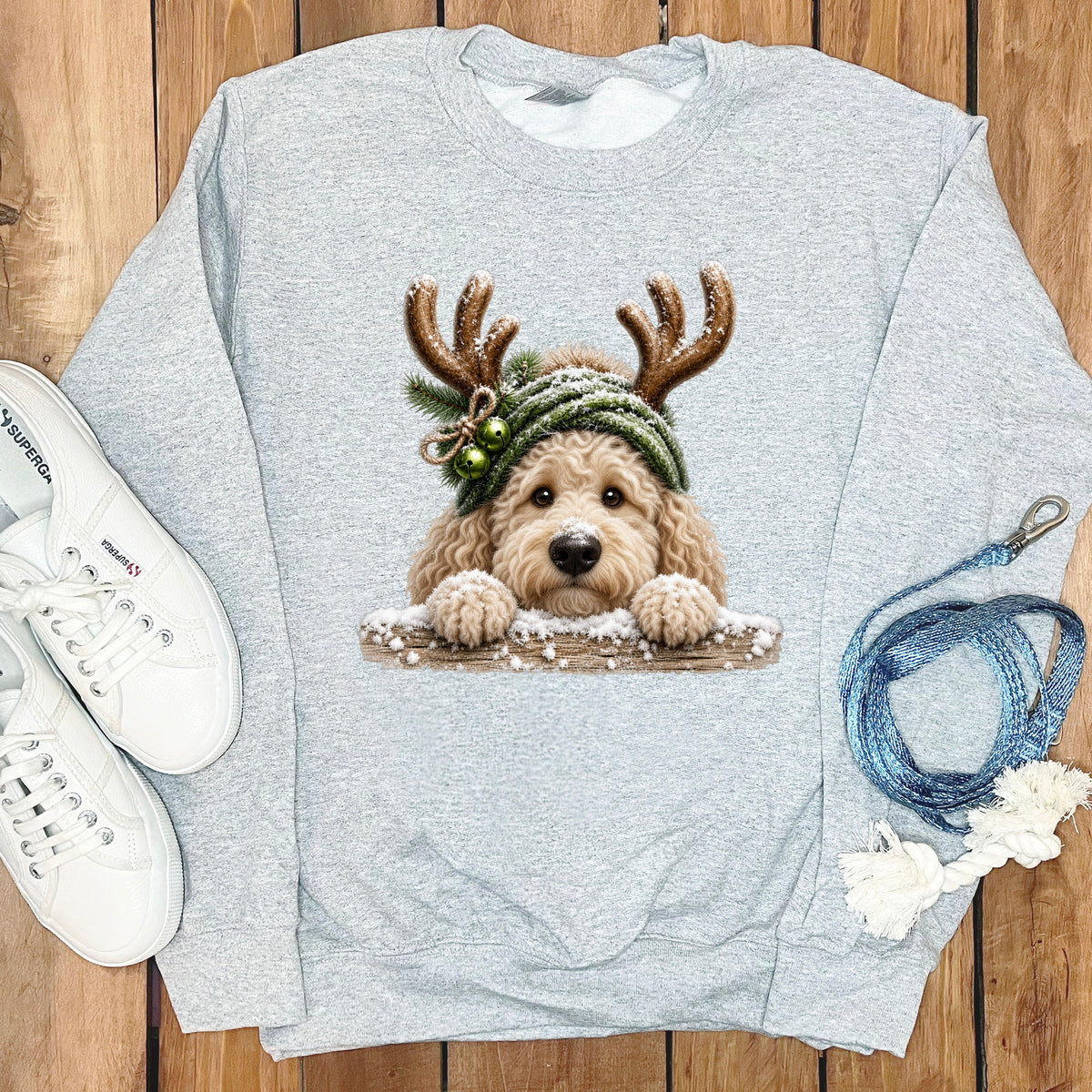 Grey sweatshirt with a goldendoodle wearing reindeer antlers and a green beanie.