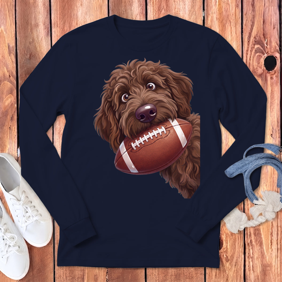 Brown doodle dog with a football in its mouth on a navy shirt.