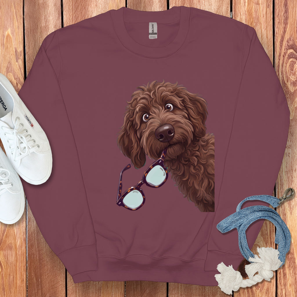 Burgundy crewneck sweatshirt featuring a graphic of a brown doodle dog holding glasses in its mouth.