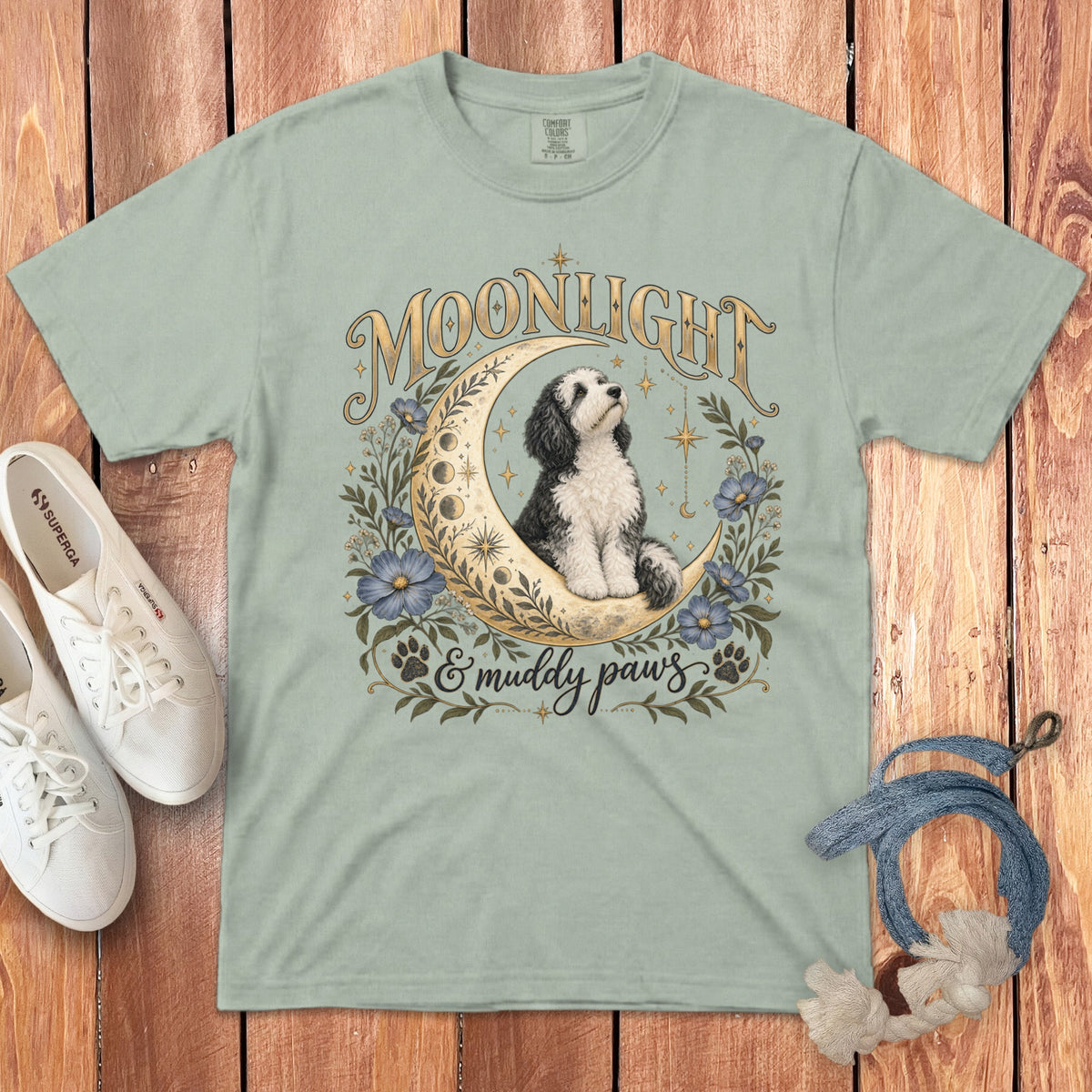 Light green t-shirt featuring a graphic of a dog sitting on a crescent moon with flowers and text.