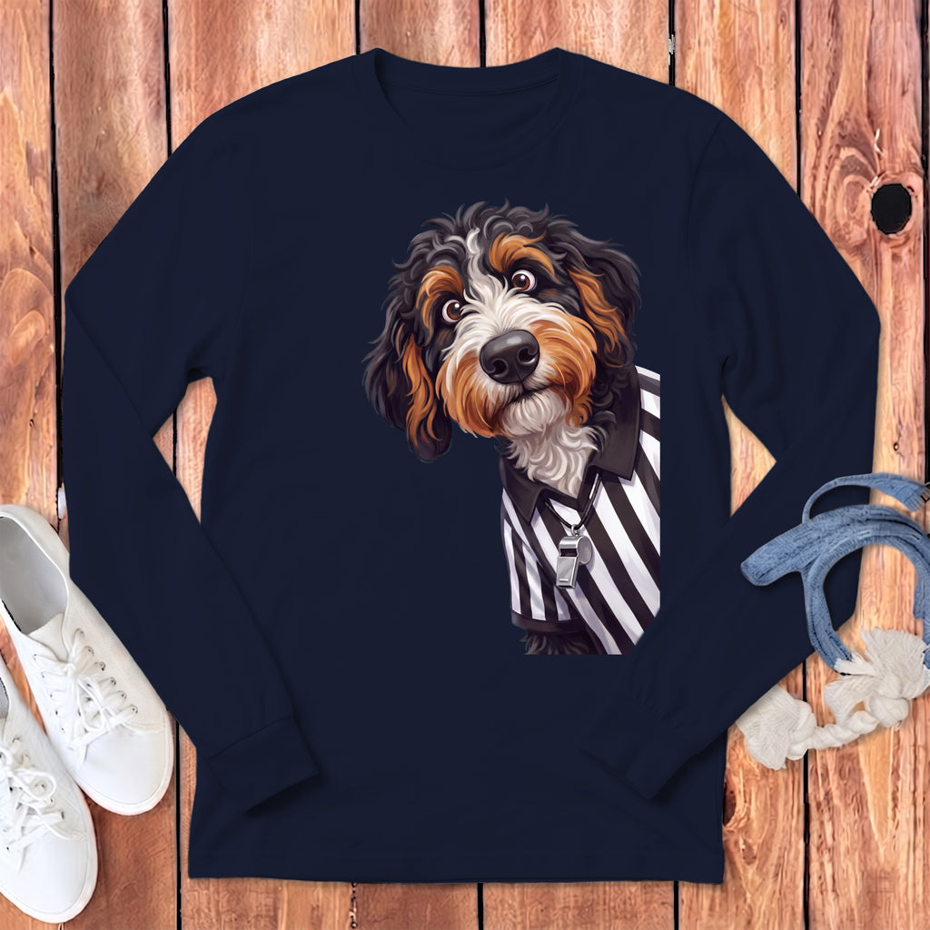 Bernedoodle dog wearing a referee shirt with whistle on a navy blue long sleeve shirt.