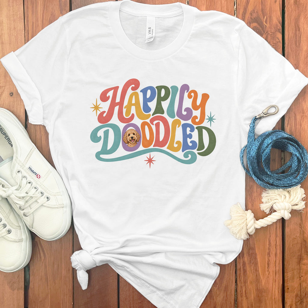 White t-shirt with "Happily Doodled" in colorful retro font and a dog's face.