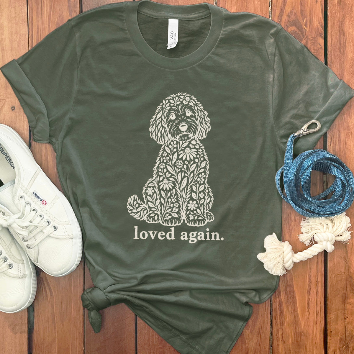 Green t-shirt with floral dog graphic and "loved again" text.