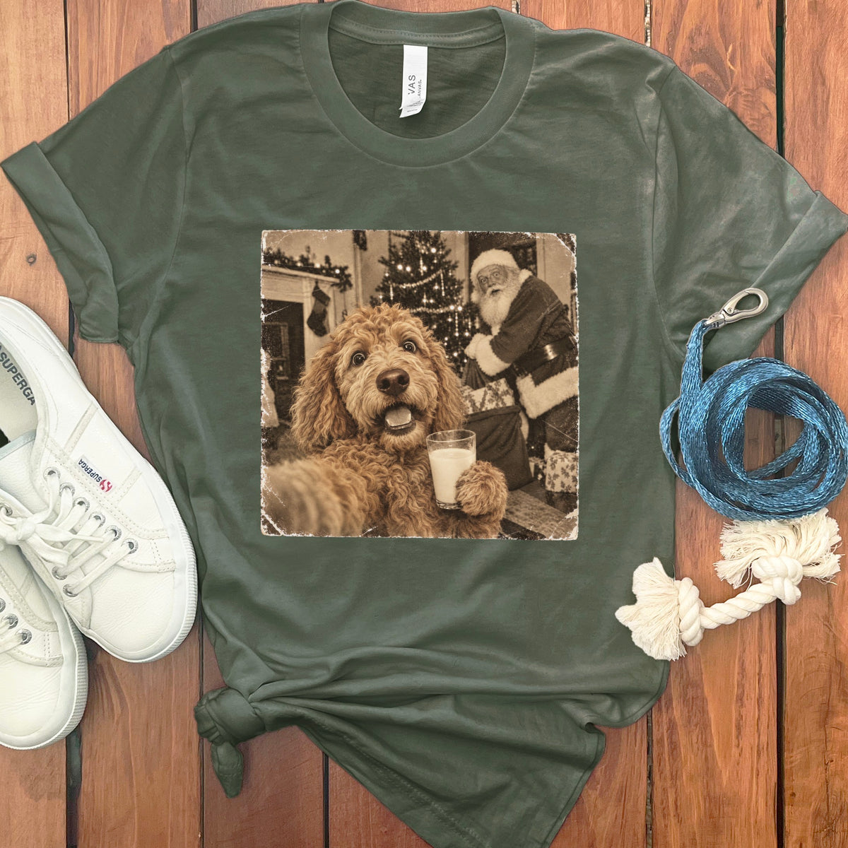 Olive green t-shirt featuring a graphic of a golden doodle holding a milk glass with Santa in the background.