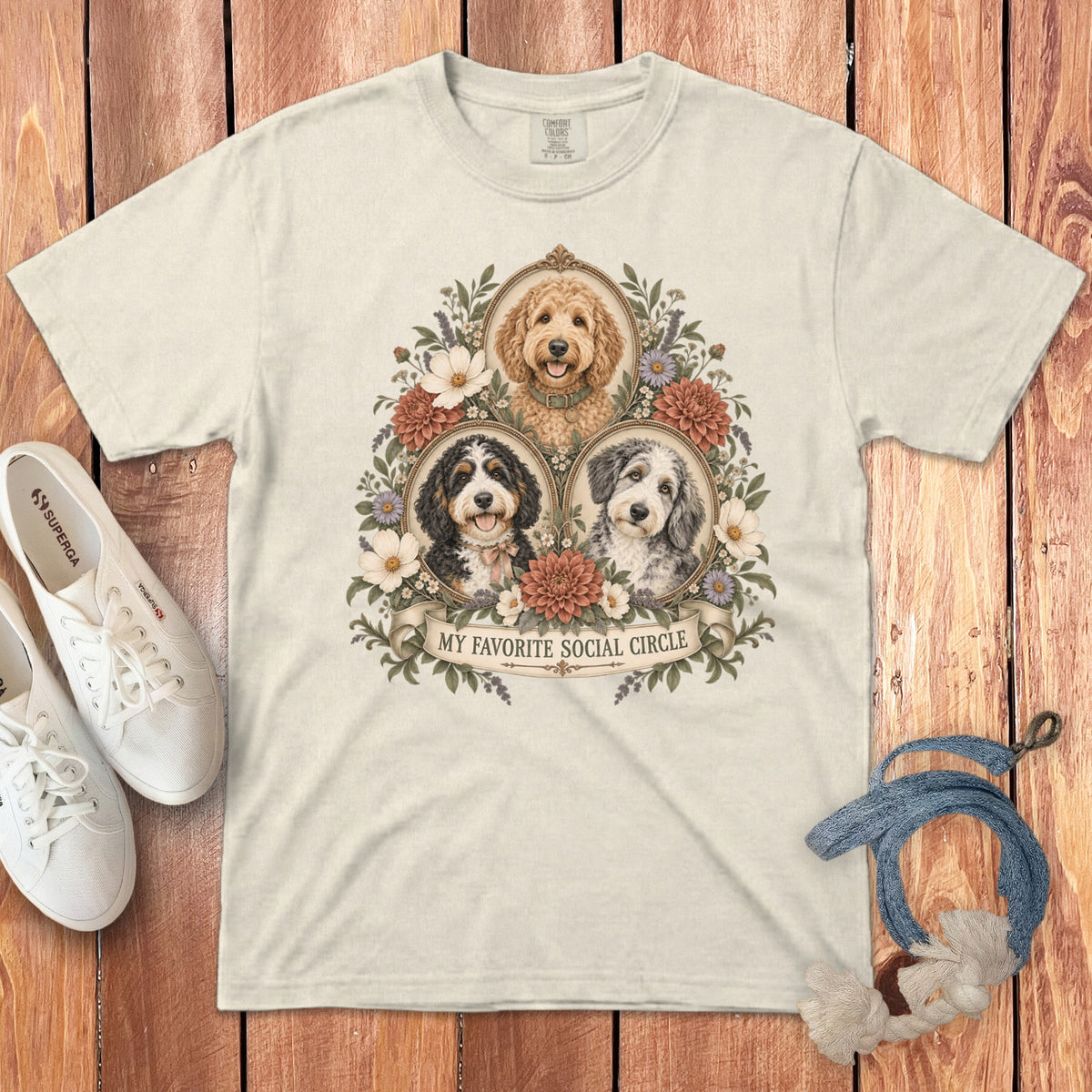 A cream t-shirt featuring a graphic of three doodle dogs framed by flowers with the text My Favorite Social Circle.