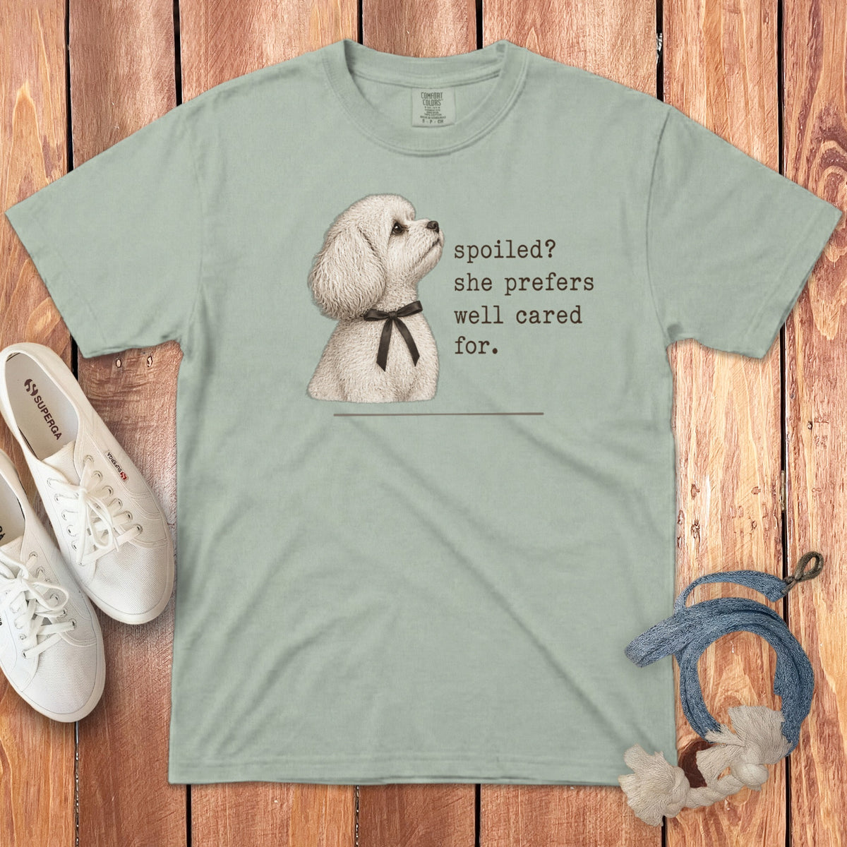Sage green crewneck t-shirt featuring a white poodle graphic and the text spoiled? she prefers well cared for.