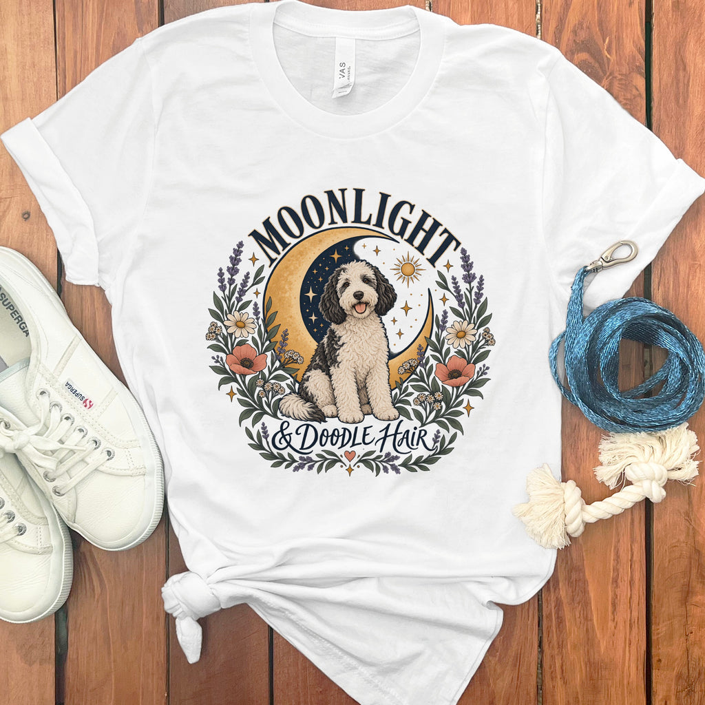 White t-shirt with a black and white doodle dog, moon, sun, and floral design reading "Moonlight & Doodle Hair".