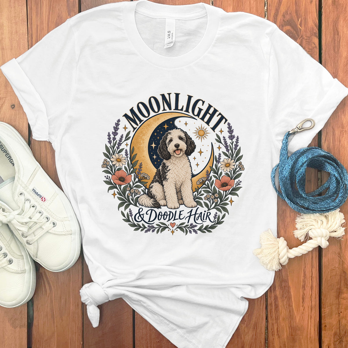 White t-shirt with a black and white doodle dog, moon, sun, and floral design reading "Moonlight & Doodle Hair".