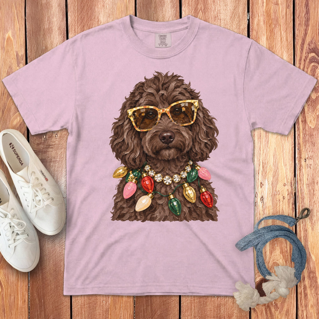 Brown dog wearing sunglasses and a Christmas light necklace on a pink t-shirt.