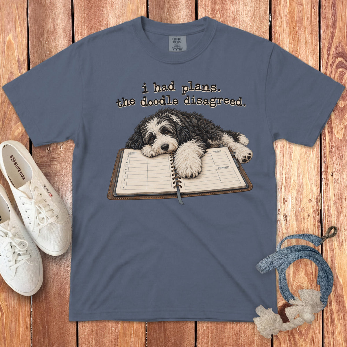 Slate blue t-shirt featuring a black and white doodle dog resting on an open planner.