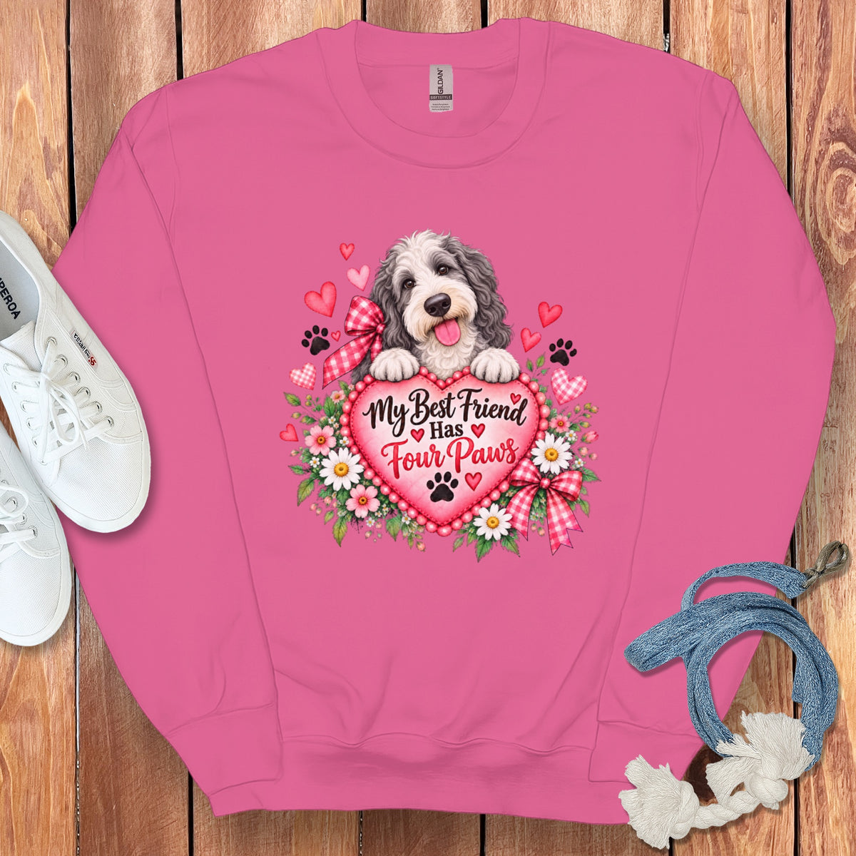 Bright pink sweatshirt featuring a dog graphic, text that reads My Best Friend Has Four Paws, surrounded by white shoes and a blue leash.