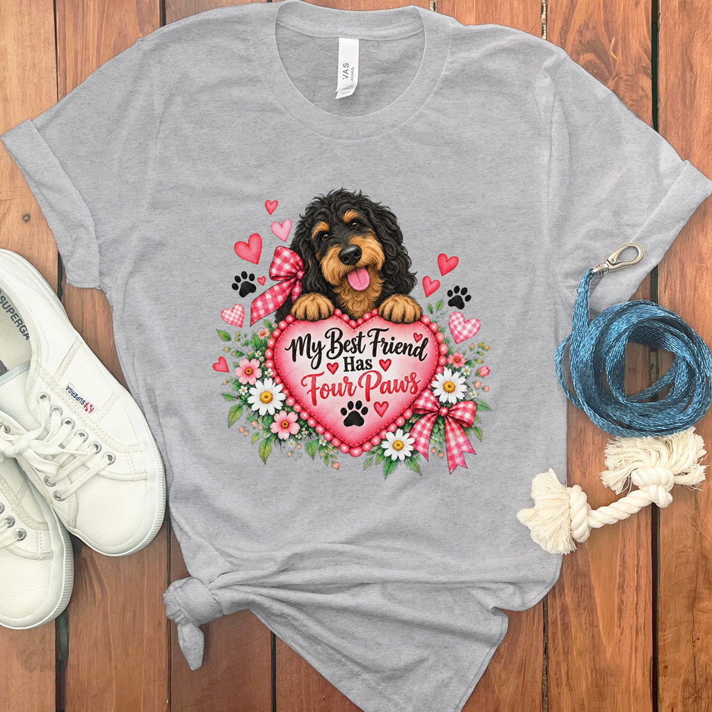 A gray t-shirt featuring a doodle dog graphic, a pink heart with text, flowers, and paw prints.
