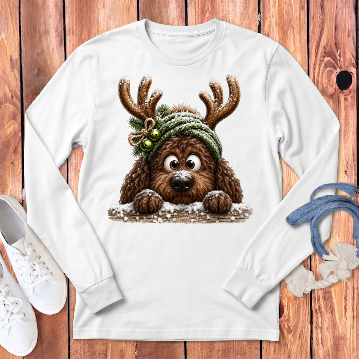 White long-sleeve shirt featuring a fluffy brown dog wearing reindeer antlers and a knit hat.