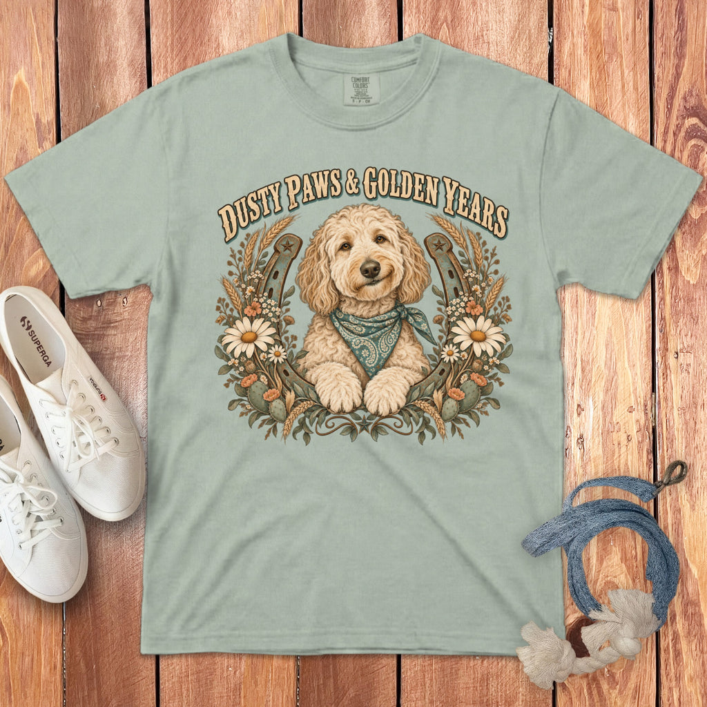 Sage green t-shirt featuring a goldendoodle wearing a bandana surrounded by horseshoes, flowers, and the text Dusty Paws & Golden Years.