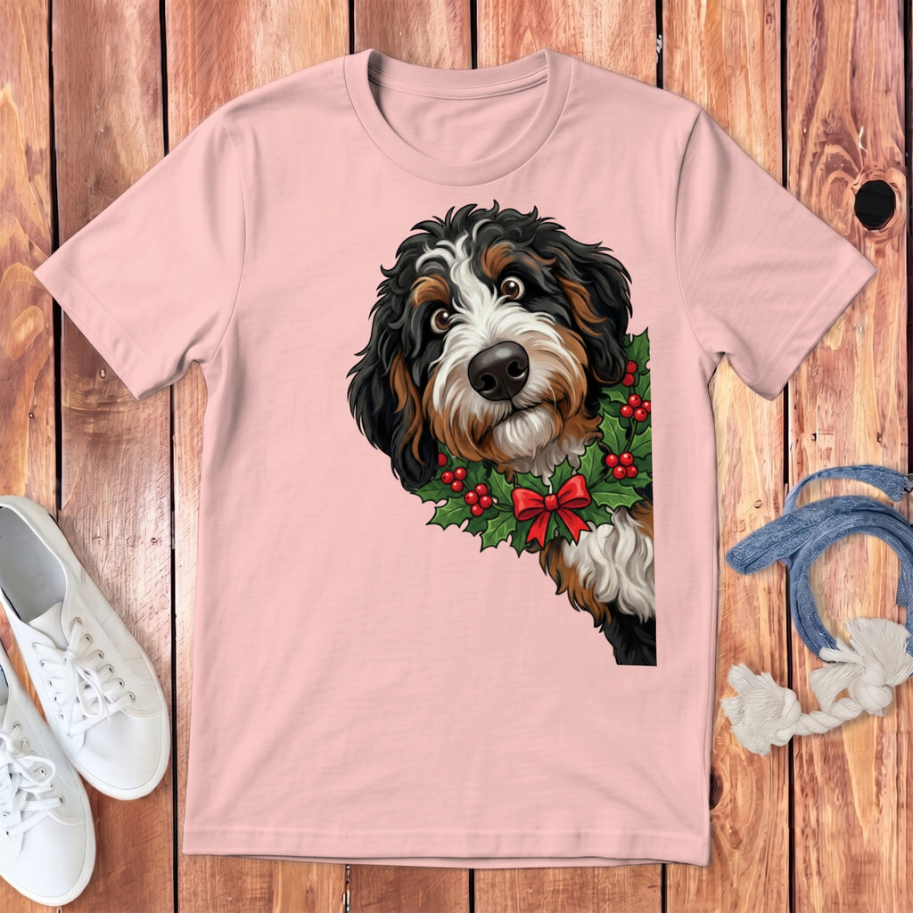 Bernese Mountain Dog wearing a holly wreath with red bow on pink t-shirt.