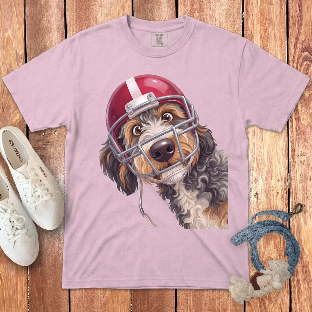 Dog wearing a red football helmet on a pink t-shirt.