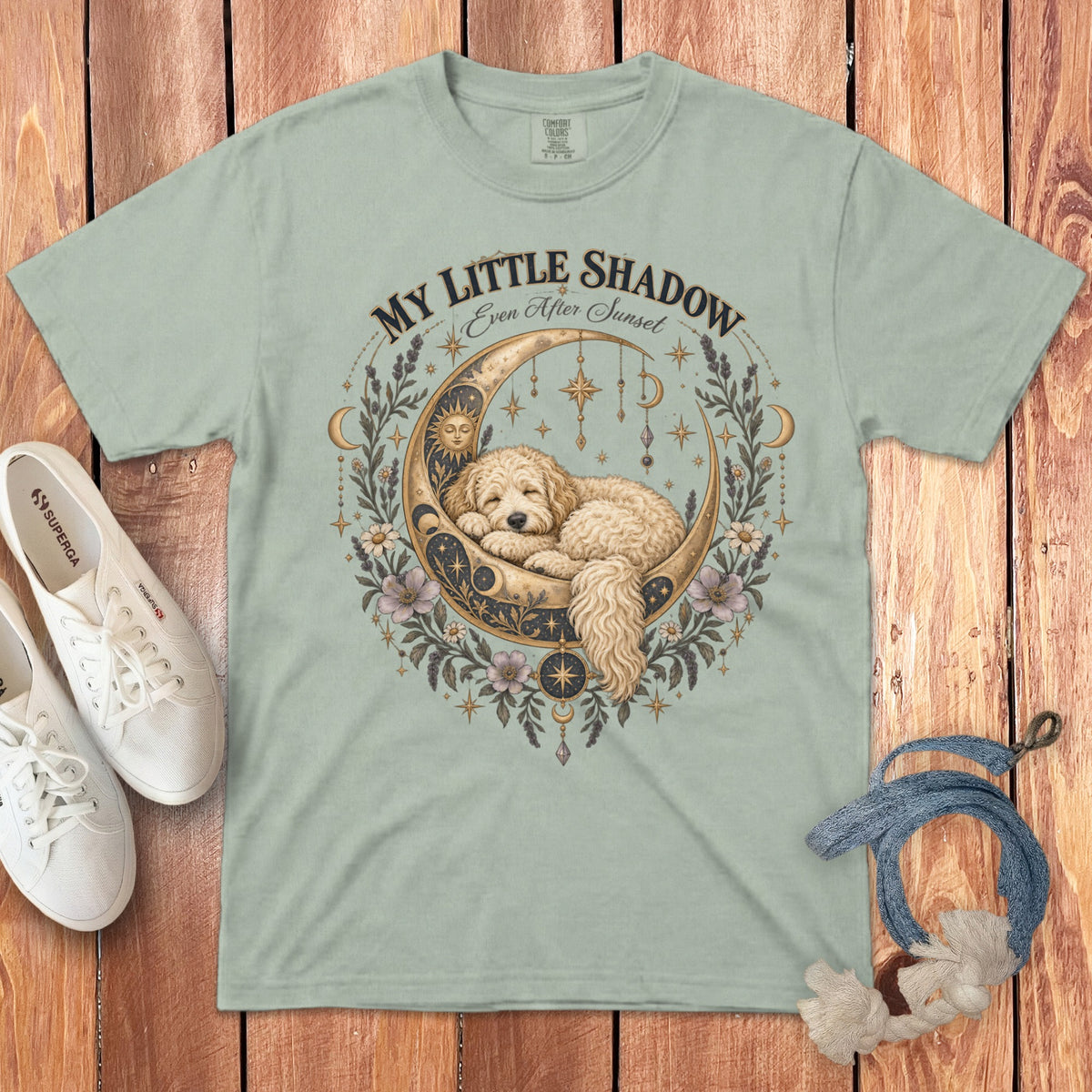 Light green t-shirt with a golden moon, sleeping dog, and celestial elements.