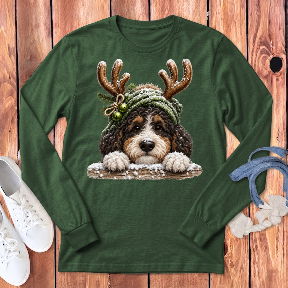 Bernedoodle dog wearing antlers and a knitted hat with bells on a green shirt.