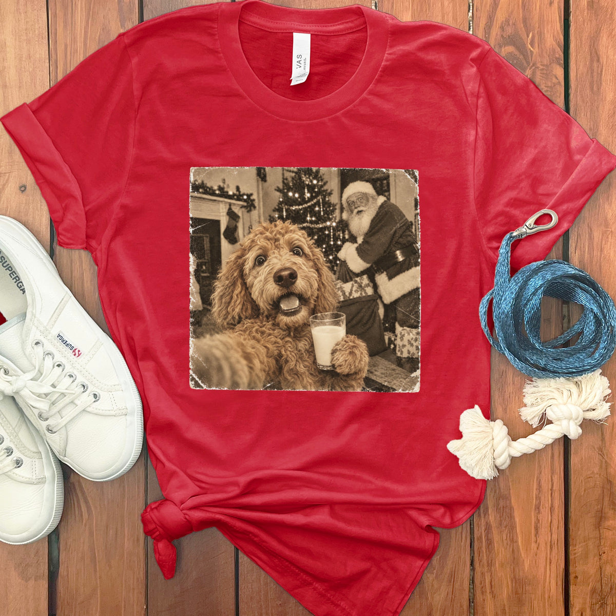 Red crewneck t-shirt featuring a black and white graphic of a fluffy dog holding a glass of milk with Santa Claus in the background.