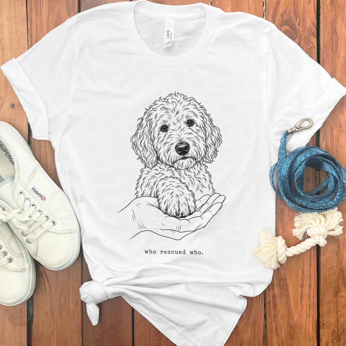 White t-shirt with a line drawing of a dog's paw on a hand and text "who rescued who."