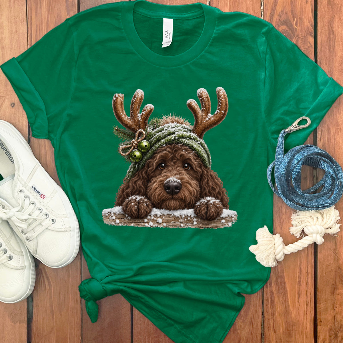 Green t-shirt featuring a fluffy brown dog wearing antlers and a beanie.