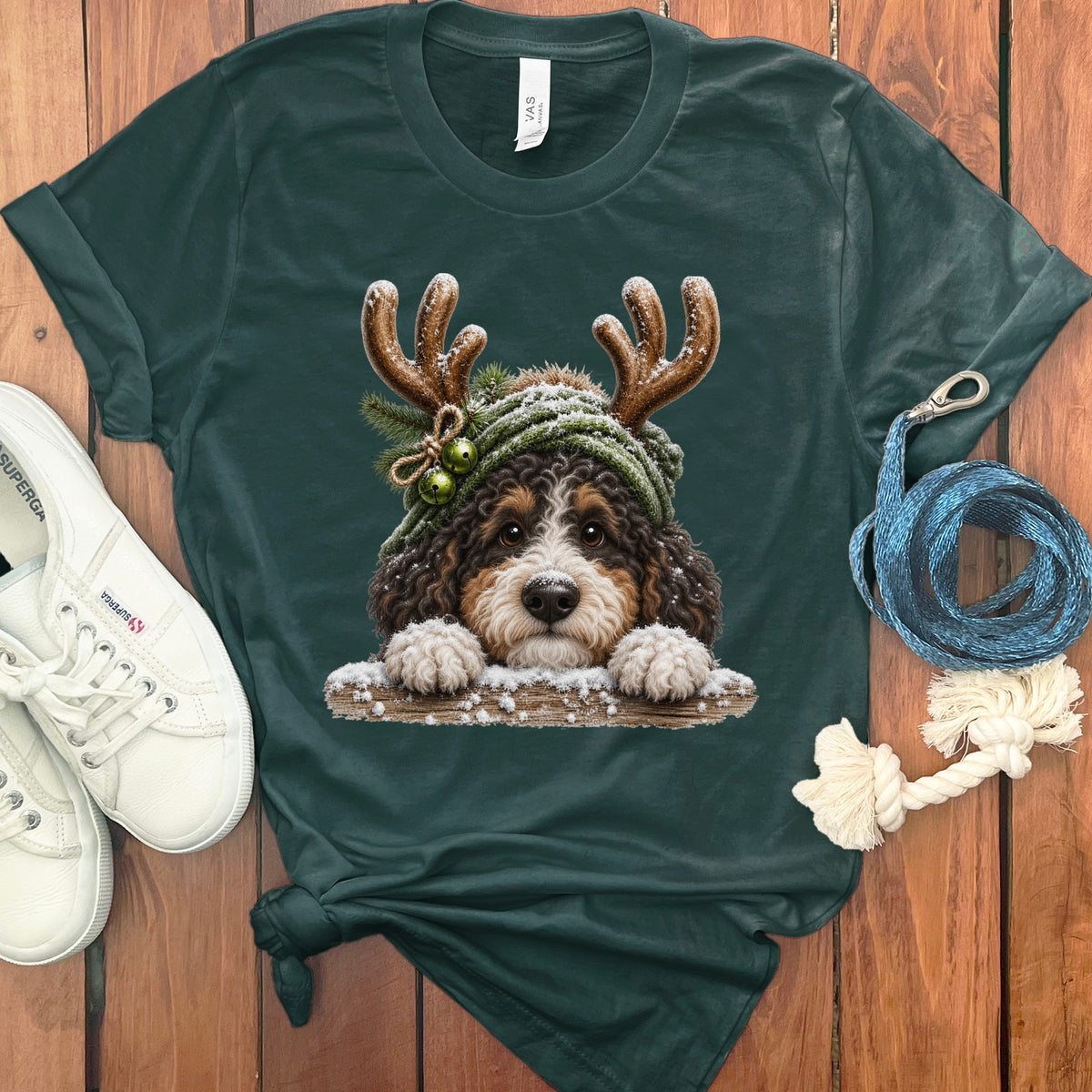 Bernedoodle puppy wearing Christmas antlers and hat, peeking over a log.