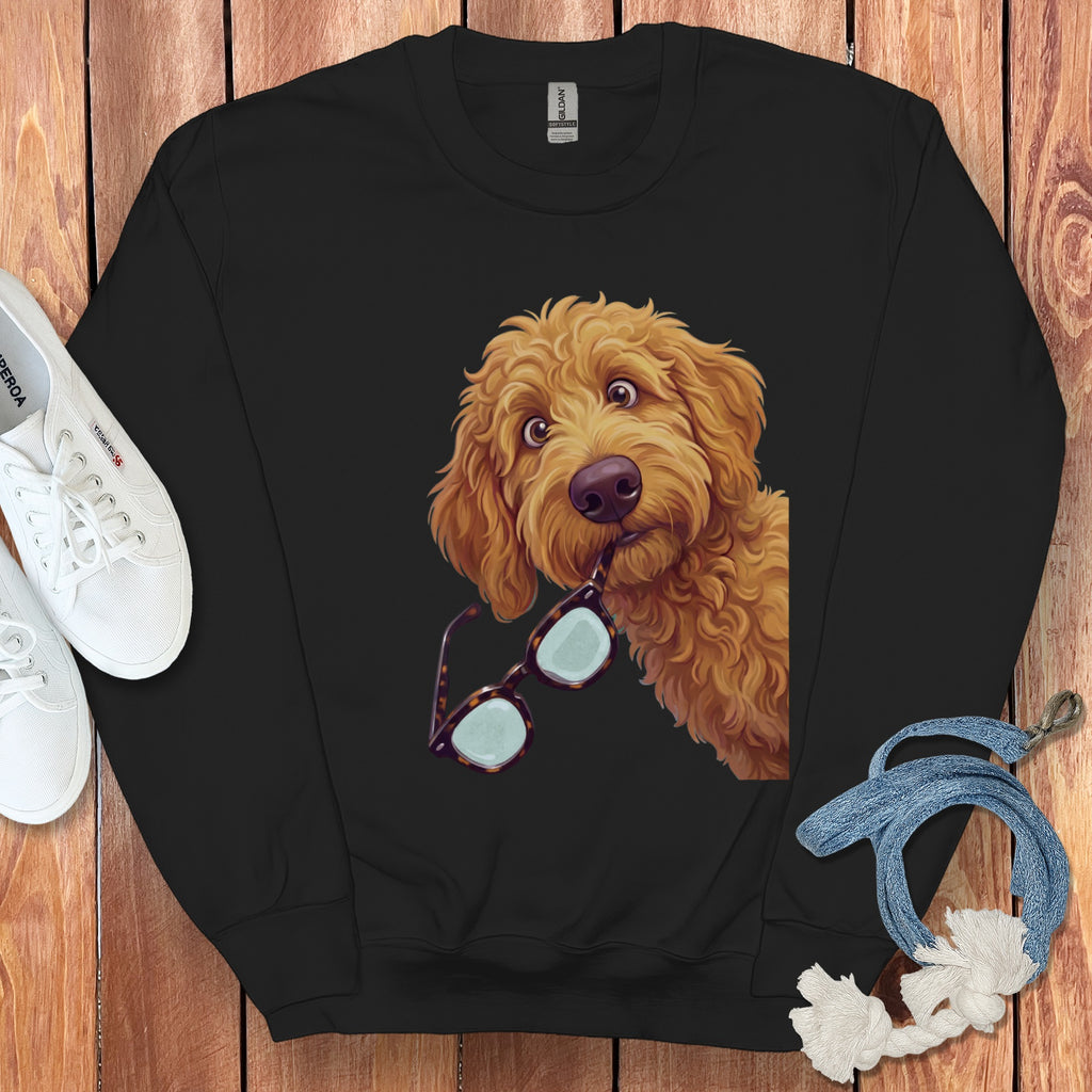 A black crewneck sweatshirt features an illustrated golden doodle dog holding tortoiseshell glasses in its mouth.
