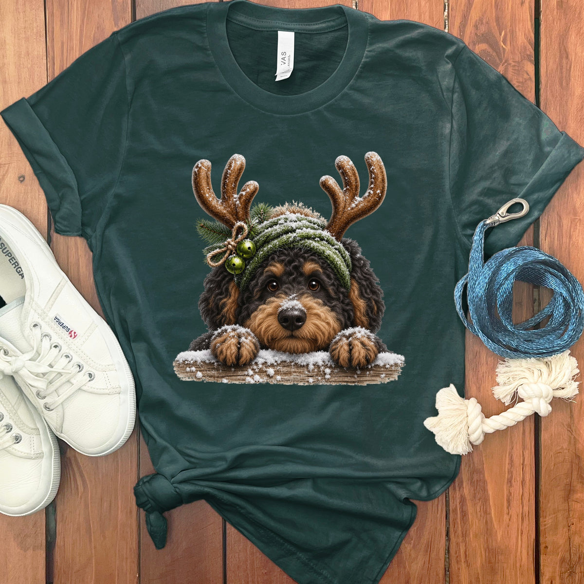 Dark green t-shirt with a fluffy dog wearing reindeer antlers and a beanie.