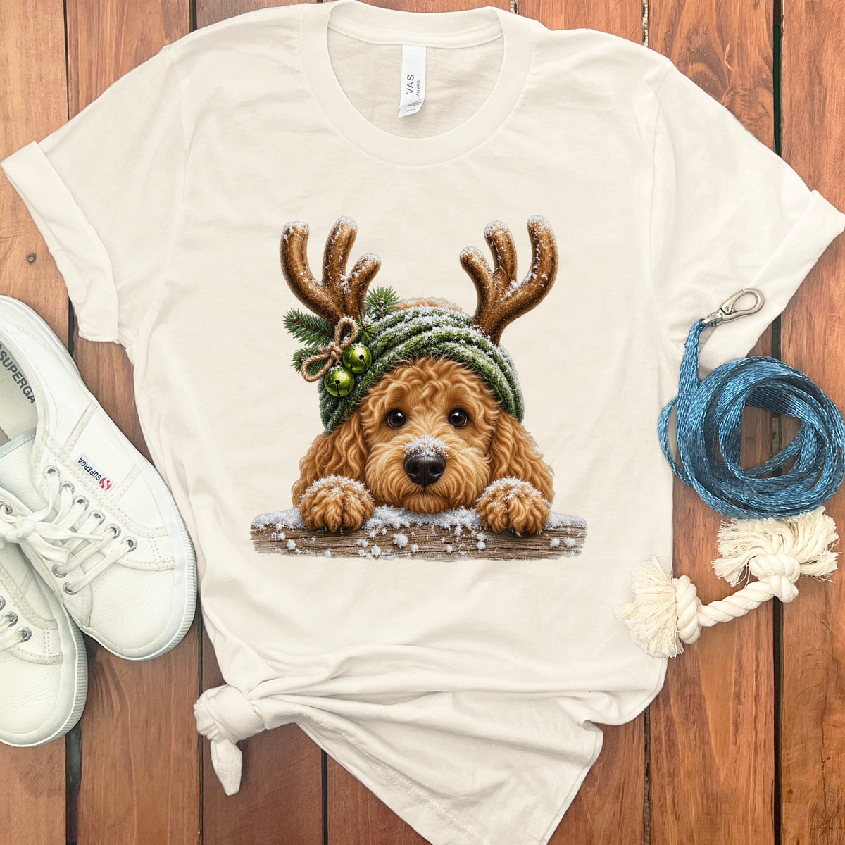 Cream t-shirt with a Christmas-themed doodle dog wearing reindeer antlers and a beanie.
