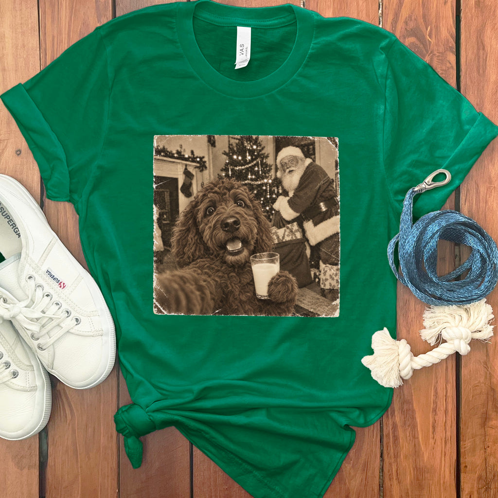A green t-shirt features a vintage photo of a brown dog holding a glass of milk with Santa Claus in the background.