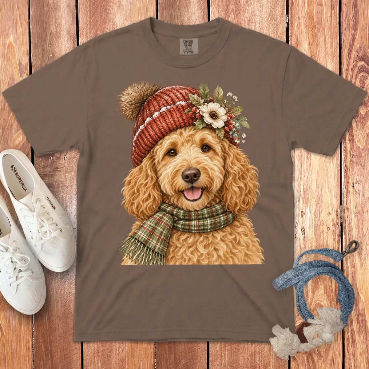 Brown t-shirt with watercolor painting of a goldendoodle wearing a knit hat and scarf.