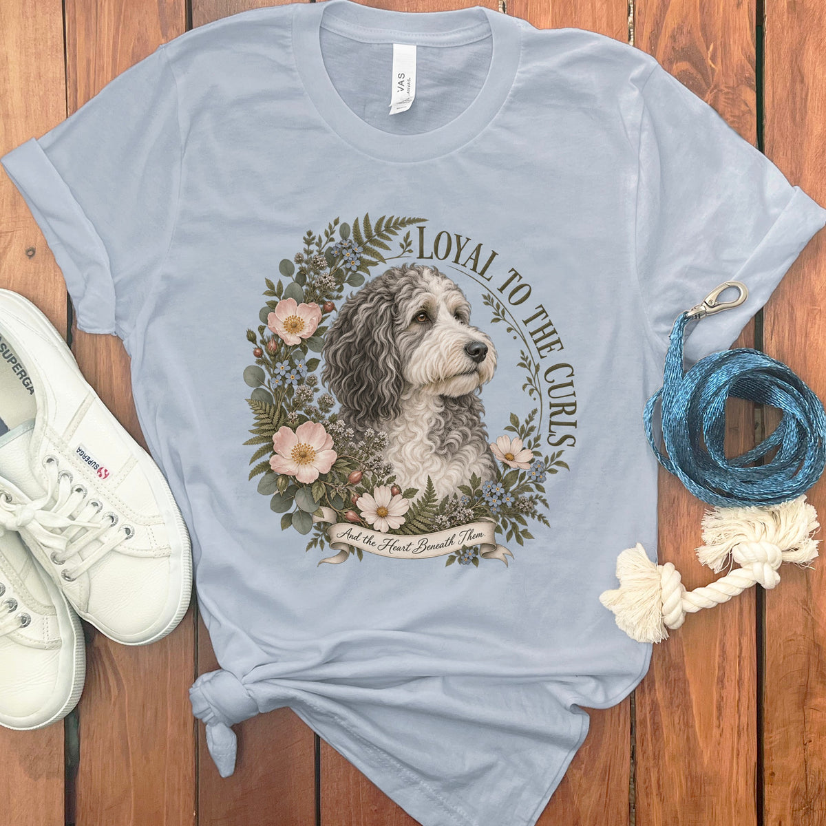 Light blue t-shirt with a doodle dog surrounded by flowers and text.