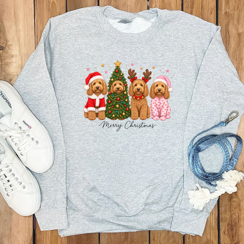A gray crewneck sweatshirt features an illustrated graphic of four doodle dogs celebrating Christmas, accompanied by white sneakers and a blue leash on a wooden background.