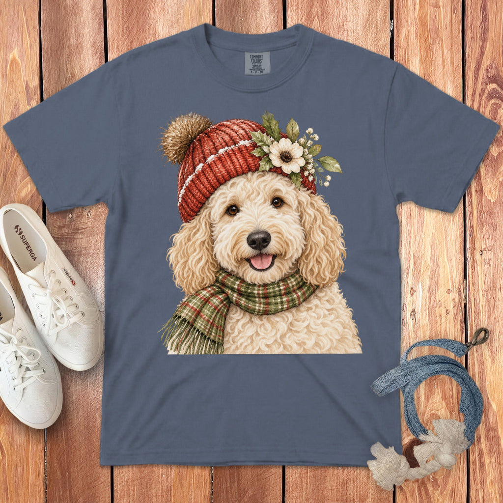 Goldendoodle in a knitted hat and scarf, with flowers on wooden background.