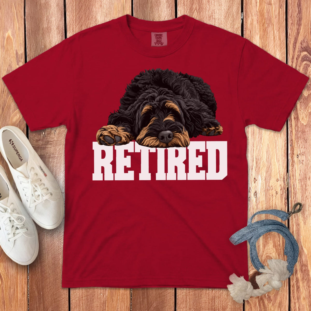 Red t-shirt with a black and tan dog lying on the word RETIRED.