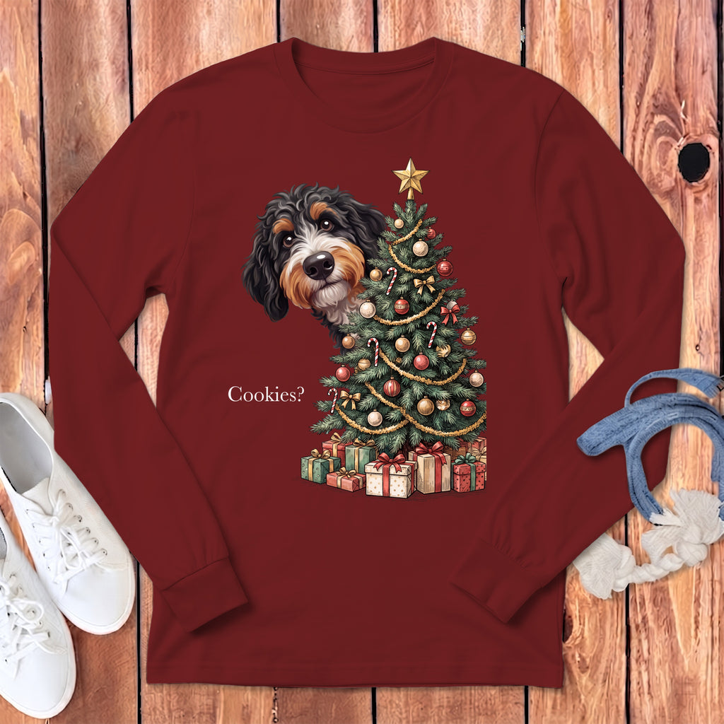 Bernedoodle peeking from behind a decorated Christmas tree with presents below, text "Cookies?"