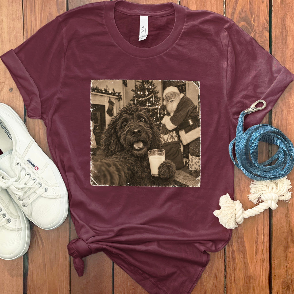Maroon t-shirt featuring a black and white graphic of a dog holding milk with Santa Claus in the background.