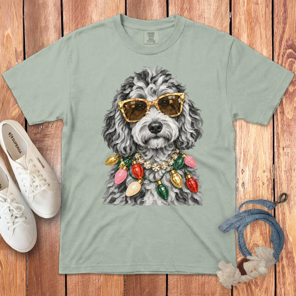 Light sage t-shirt with graphic of fluffy dog wearing sunglasses and Christmas lights necklace.