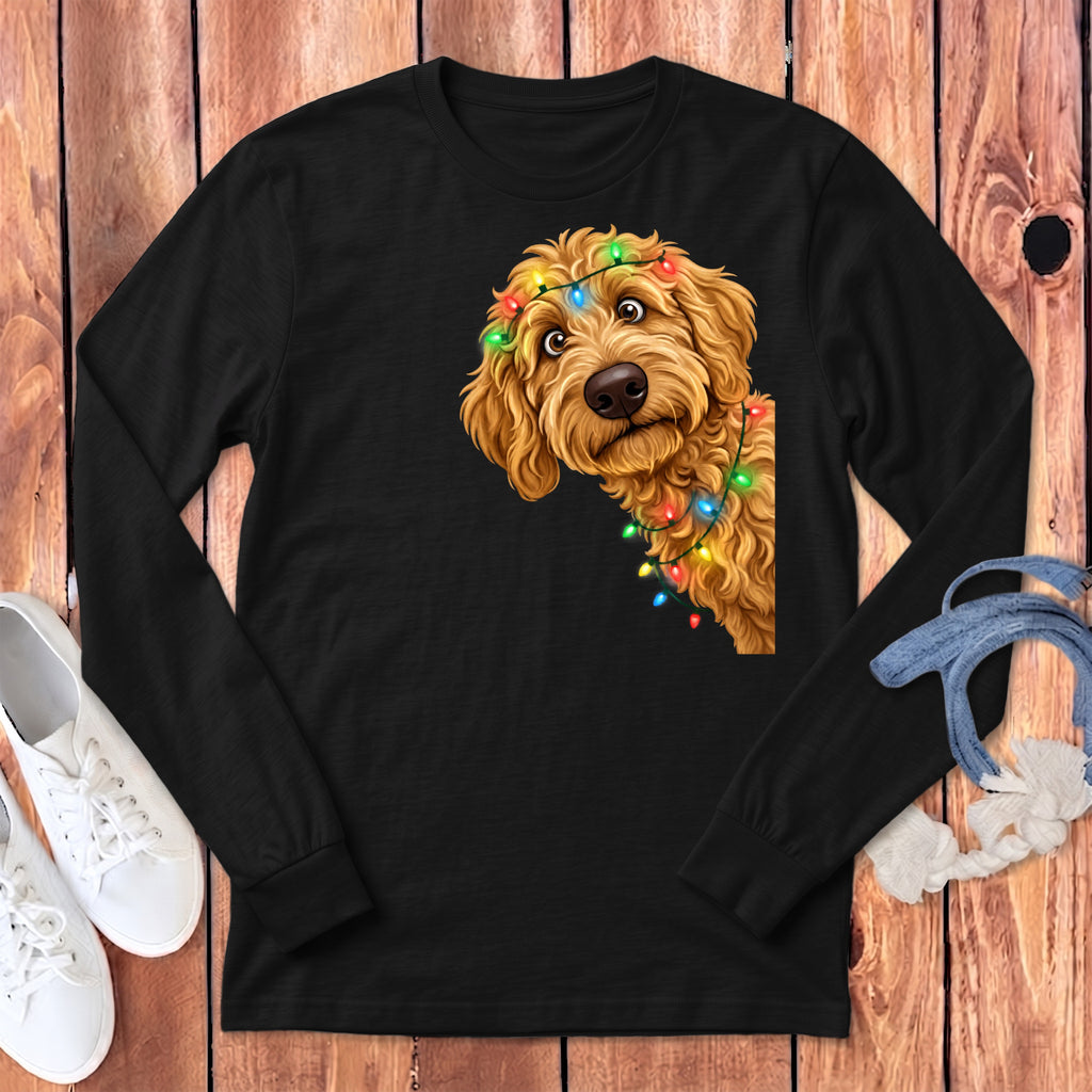 Goldendoodle dog peeking out from behind Christmas lights on black long sleeve shirt.
