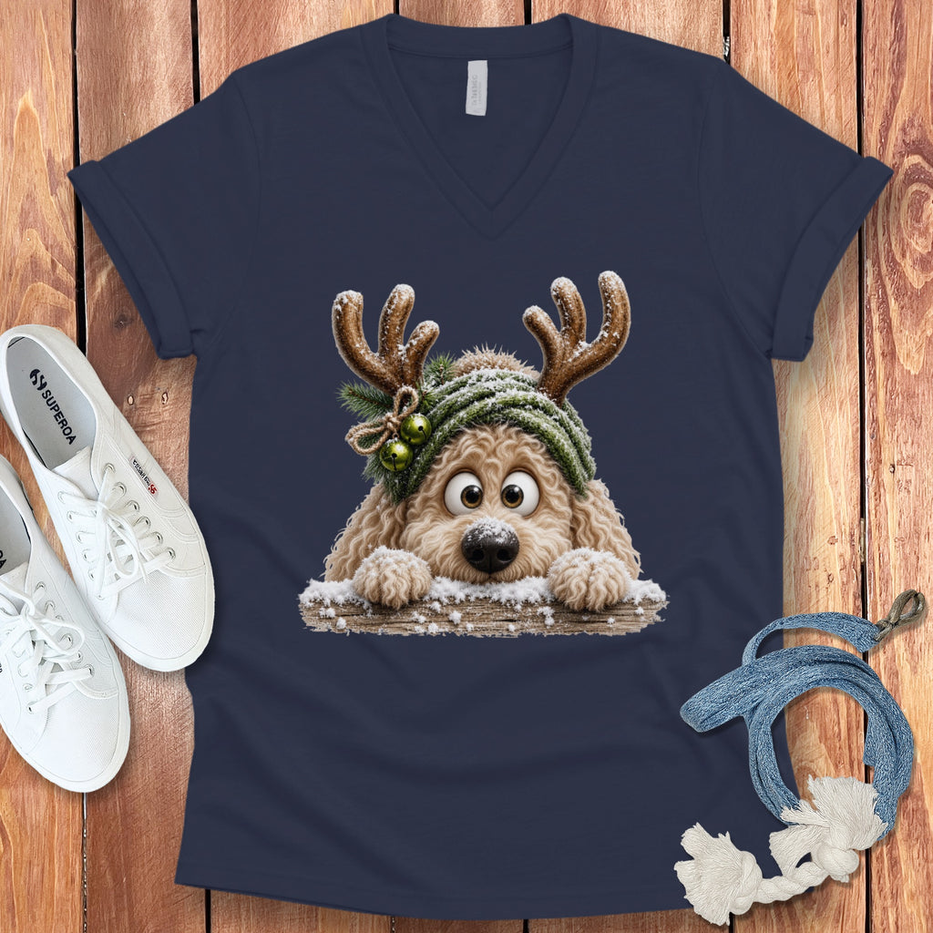 Fluffy cartoon dog wearing reindeer antlers and a green hat peeks over a snowy log.