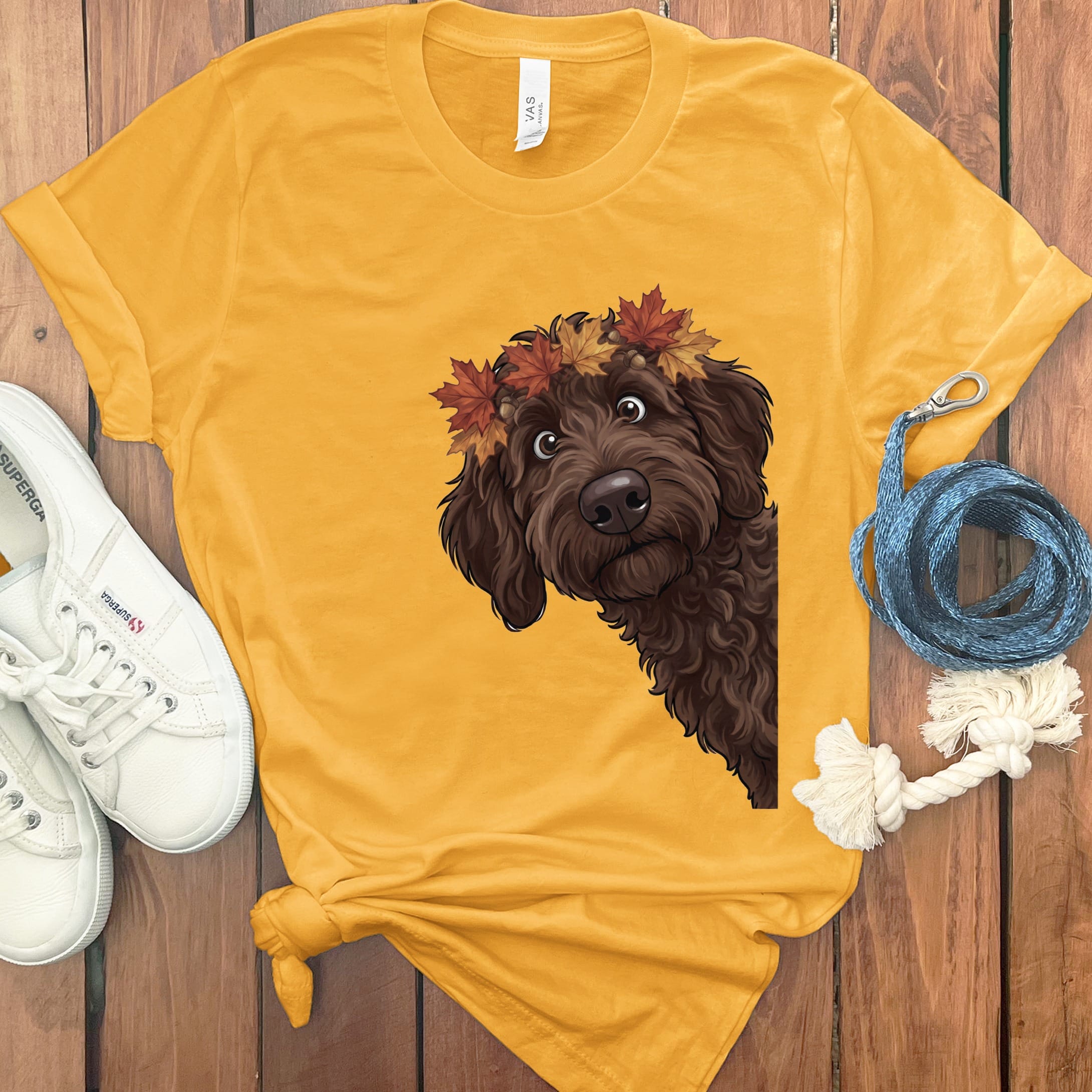 Brown doodle dog wearing autumn leaves crown on yellow t-shirt.